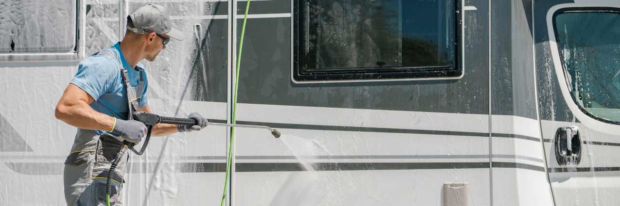 Man pressure washing the exterior of a motorhome to prepare it for long-term RV storage.